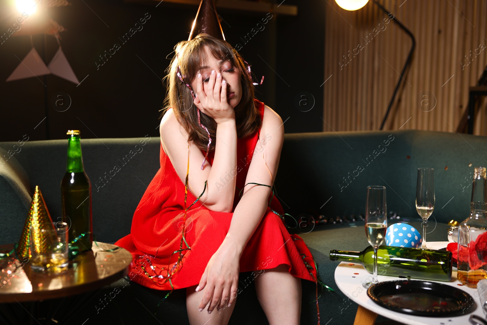 Woman suffering from hangover on sofa in messy room after party Photo of Woman suffering from hangover on sofa in messy room after party