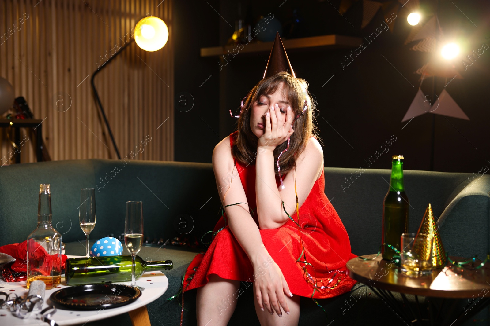 Photo of Woman suffering from hangover in messy room after party