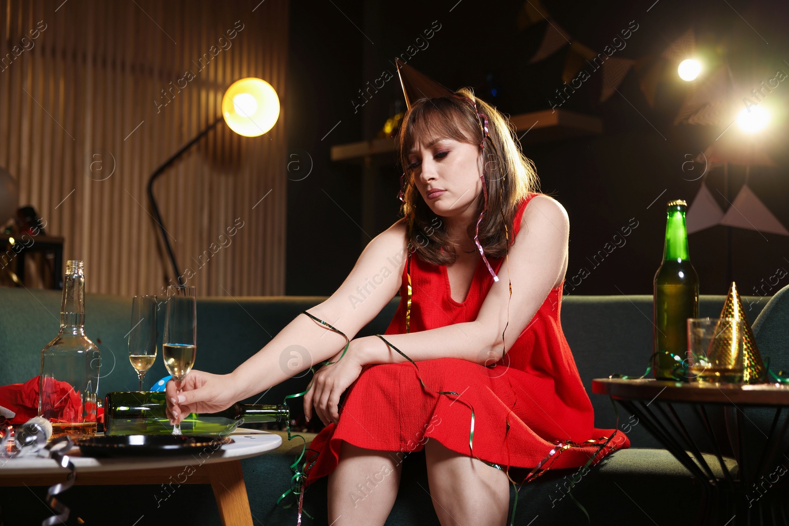 Woman with glass of alcohol suffering from hangover on sofa in messy room after party Photo of Woman with glass of alcohol suffering from hangover on sofa in messy room after party