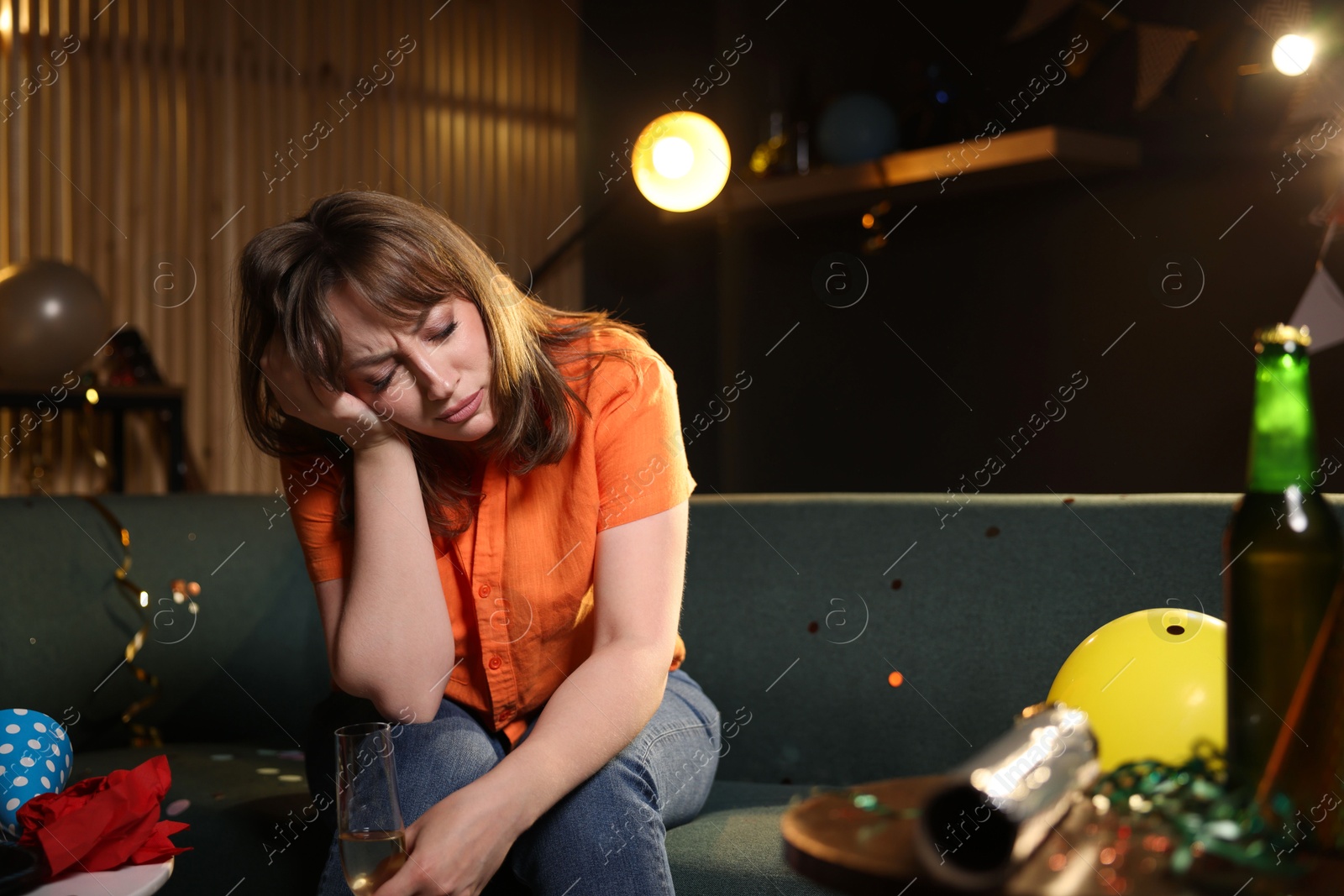Woman with glass of alcohol suffering from hangover on sofa in messy room after party Photo of Woman with glass of alcohol suffering from hangover on sofa in messy room after party