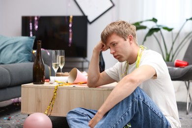 Photo of Man suffering from hangover in messy room after party
