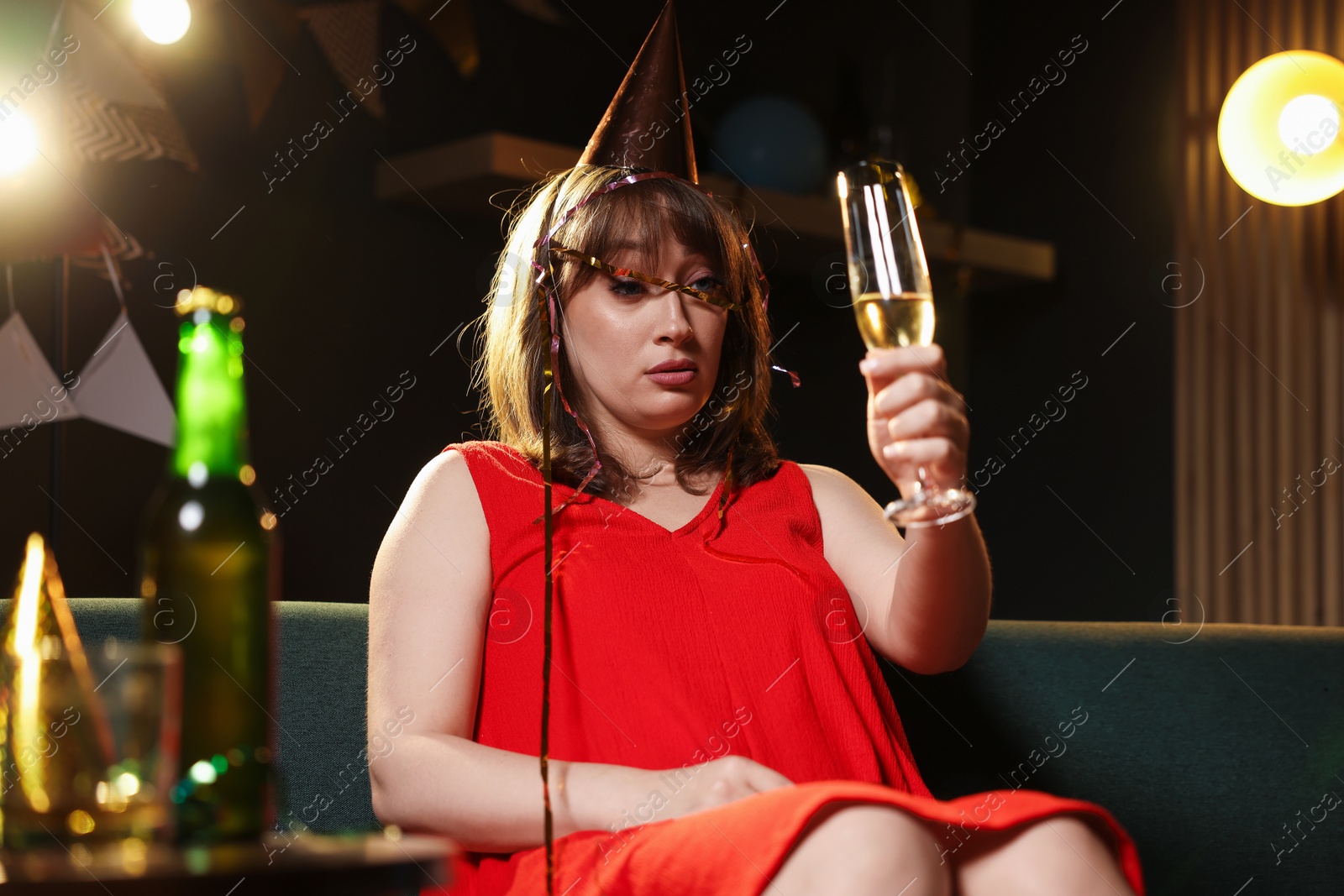 Woman with glass of alcohol suffering from hangover on sofa in messy room after party Photo of Woman with glass of alcohol suffering from hangover on sofa in messy room after party