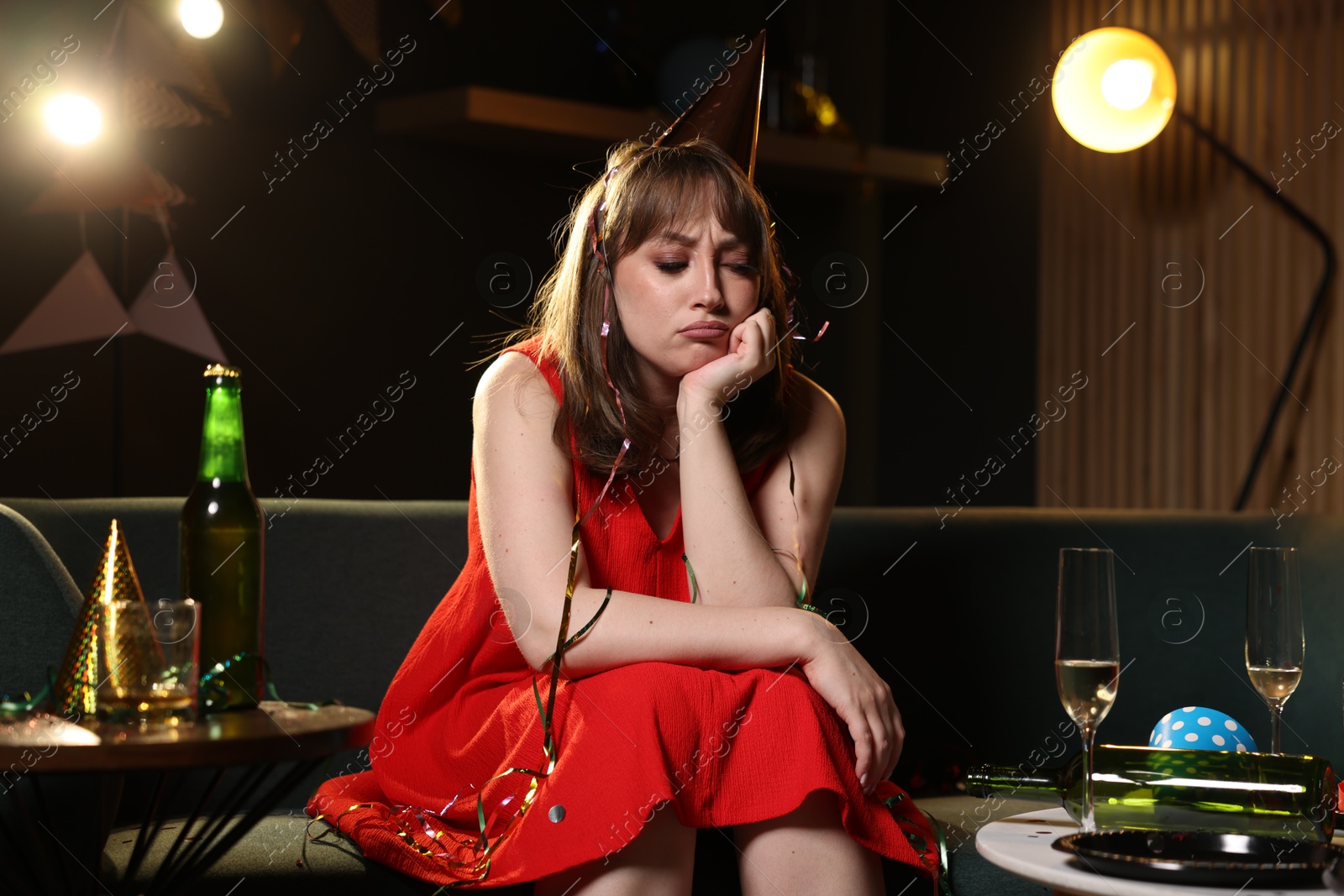 Photo of Woman suffering from hangover on sofa in messy room after party