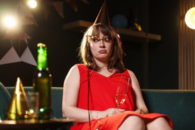 Photo of Woman suffering from hangover on sofa in messy room after party