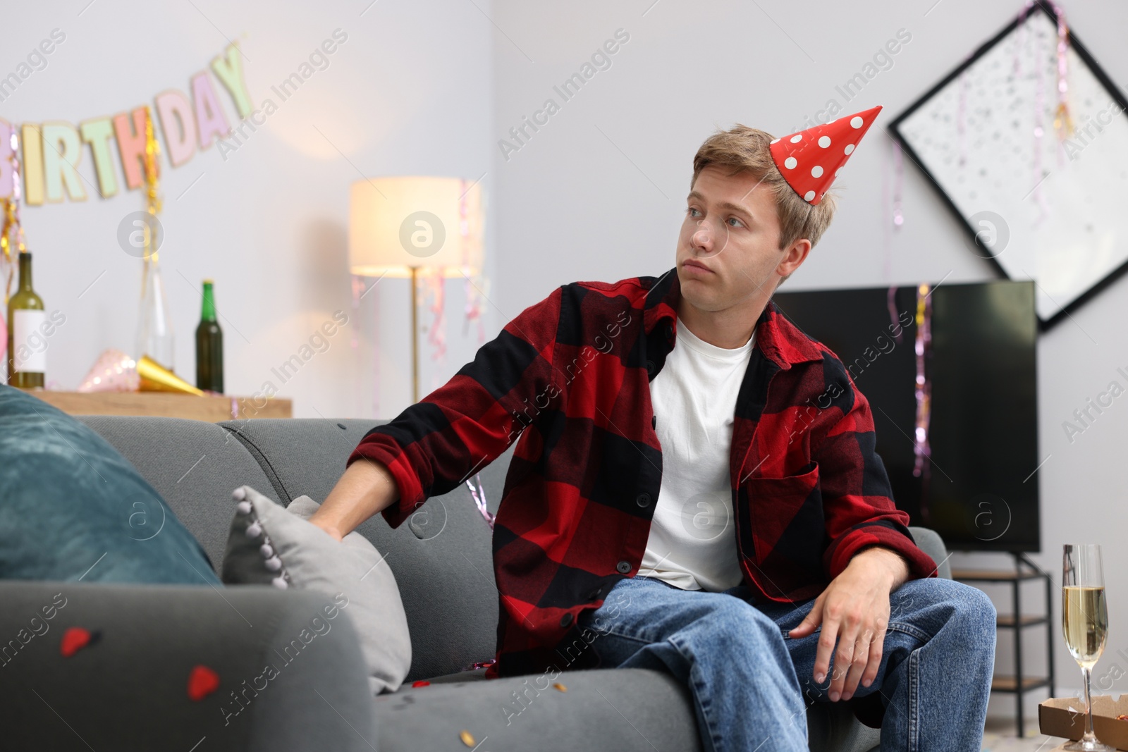 Man suffering from hangover on sofa in messy room after party Photo of Man suffering from hangover on sofa in messy room after party