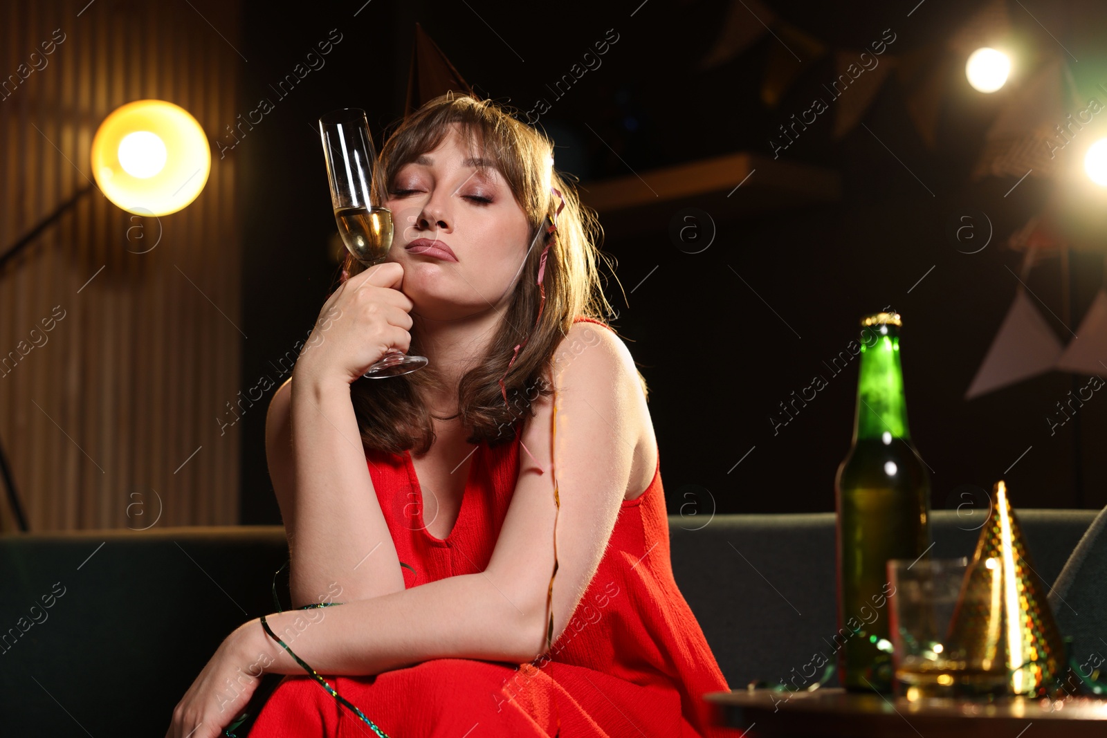 Woman with glass of alcohol suffering from hangover on sofa in messy room after party Photo of Woman with glass of alcohol suffering from hangover on sofa in messy room after party