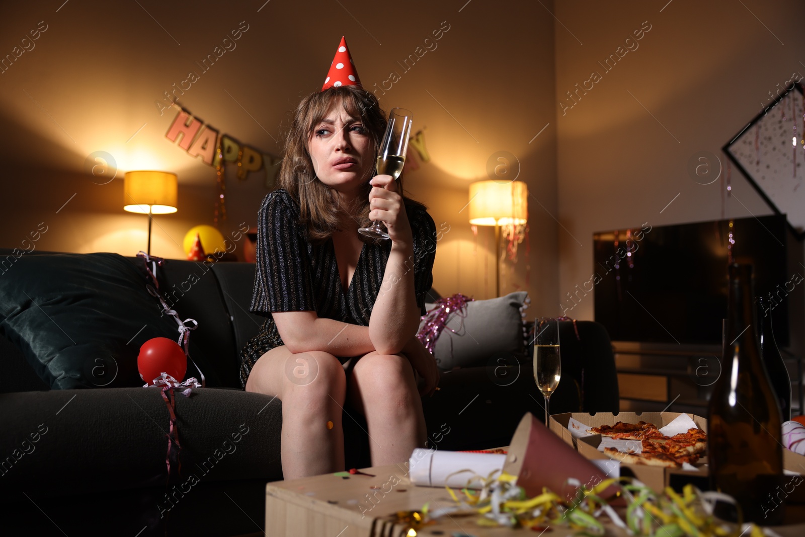 Woman with glass of alcohol suffering from hangover on sofa in messy room after party Photo of Woman with glass of alcohol suffering from hangover on sofa in messy room after party