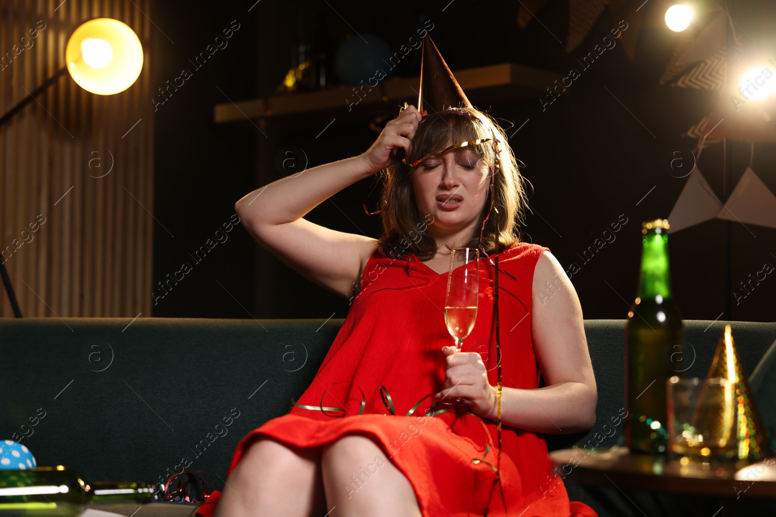 Woman with glass of alcohol suffering from hangover on sofa in messy room after party Photo of Woman with glass of alcohol suffering from hangover on sofa in messy room after party