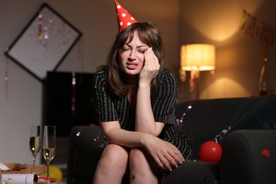Photo of Woman suffering from hangover on sofa in messy room after party