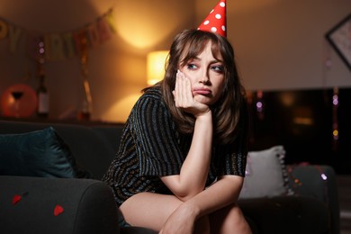Photo of Woman suffering from hangover on sofa in messy room after party