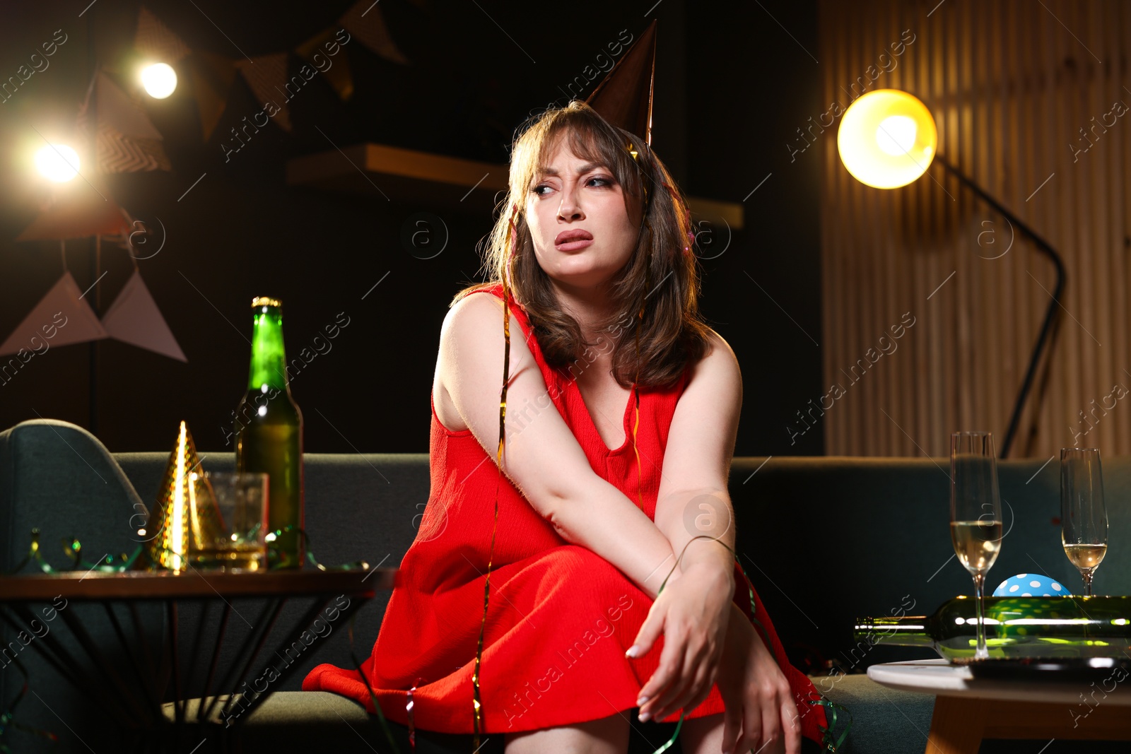 Photo of Woman suffering from hangover on sofa in messy room after party