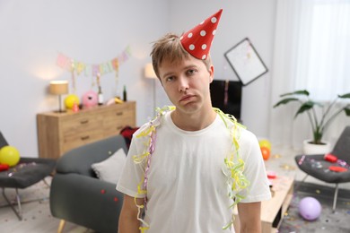 Photo of Man suffering from hangover in messy room after party