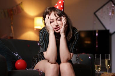 Photo of Woman suffering from hangover on sofa in messy room after party