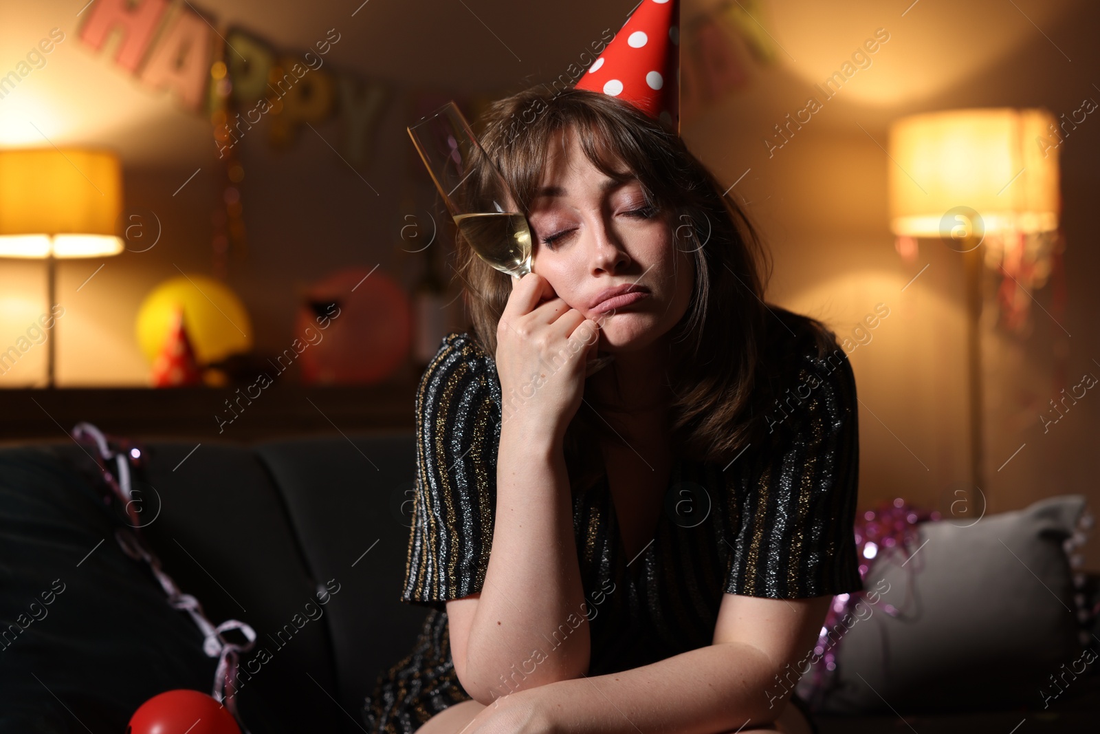 Woman with glass of alcohol suffering from hangover on sofa in messy room after party Photo of Woman with glass of alcohol suffering from hangover on sofa in messy room after party