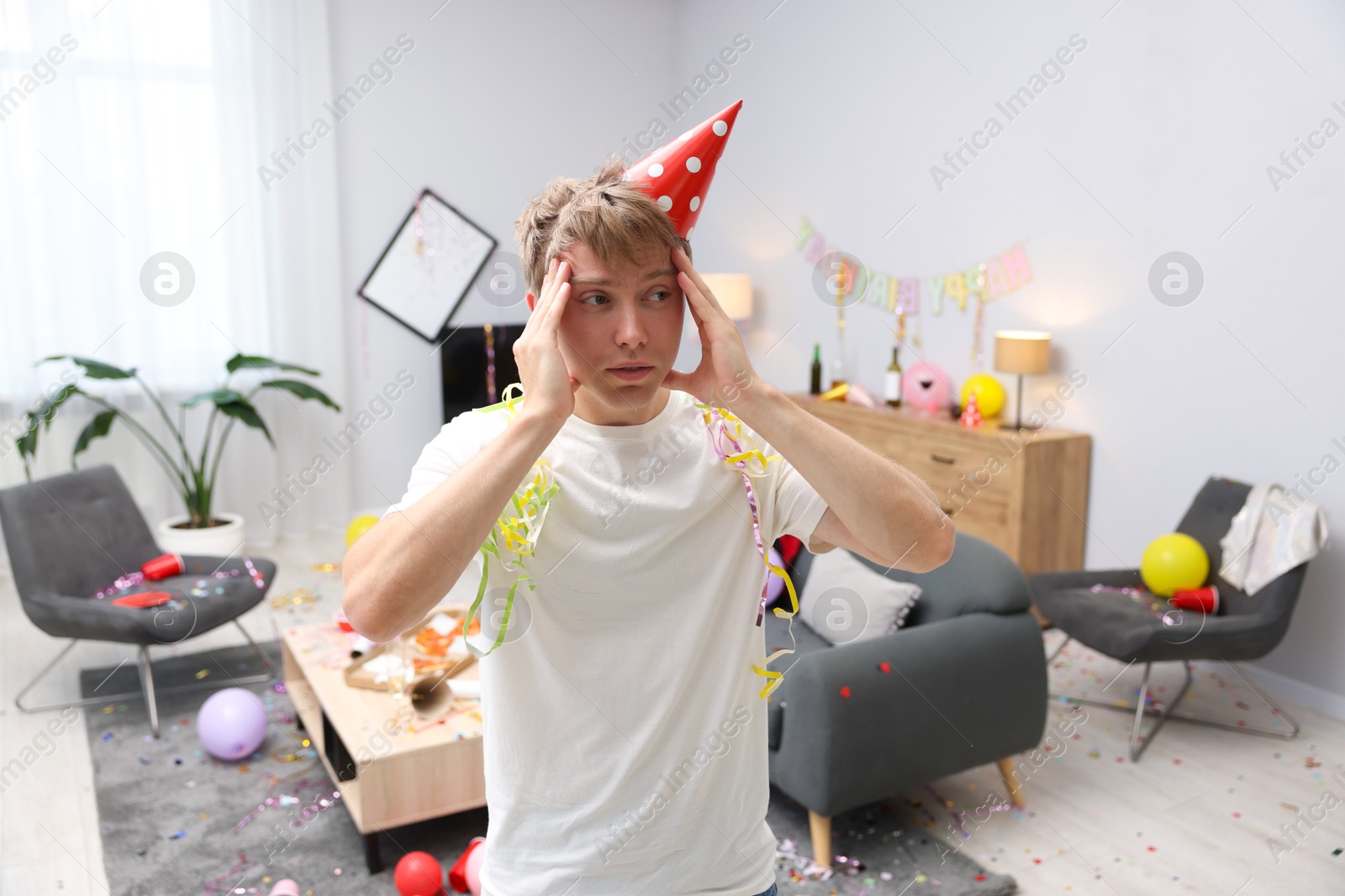 Man suffering from hangover in messy room after party Photo of Man suffering from hangover in messy room after party
