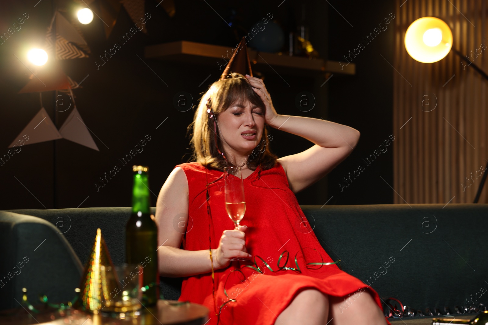 Woman with glass of alcohol suffering from hangover on sofa in messy room after party Photo of Woman with glass of alcohol suffering from hangover on sofa in messy room after party
