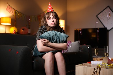 Photo of Woman with pillow suffering from hangover on sofa in messy room after party