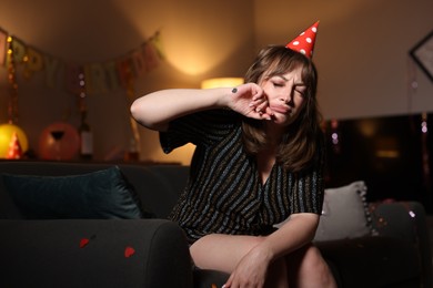 Photo of Woman suffering from hangover on sofa in messy room after party