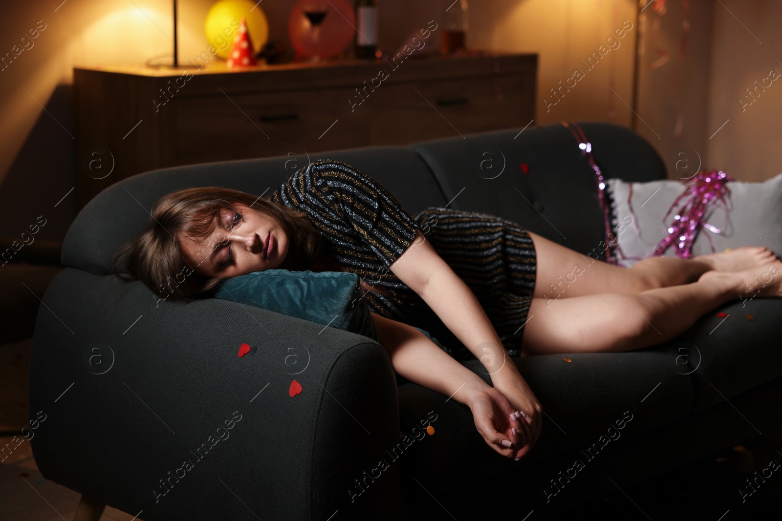 Photo of Woman suffering from hangover on sofa in messy room after party