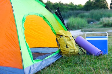 Photo of Colorful camping tent and tourist equipment on green grass outdoors