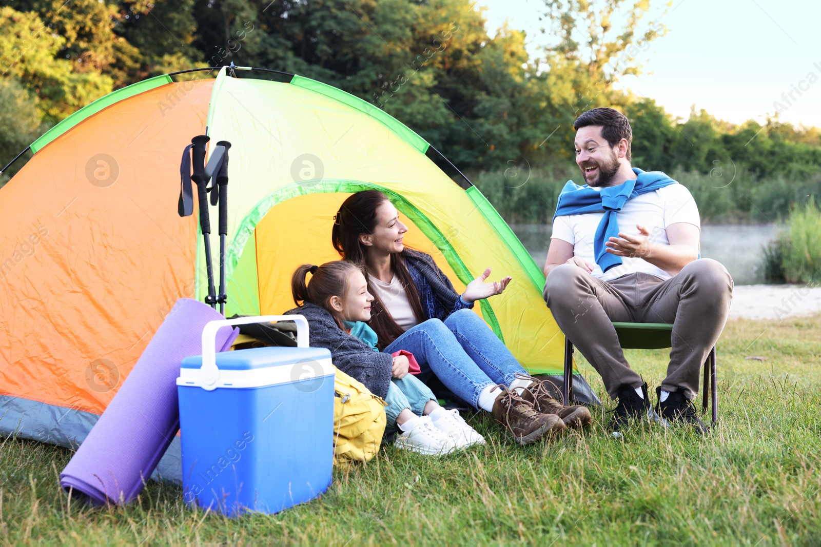 Happy family spending time together with camping tent and tourist equipment on green grass outdoors Photo of Happy family spending time together with camping tent and tourist equipment on green grass outdoors