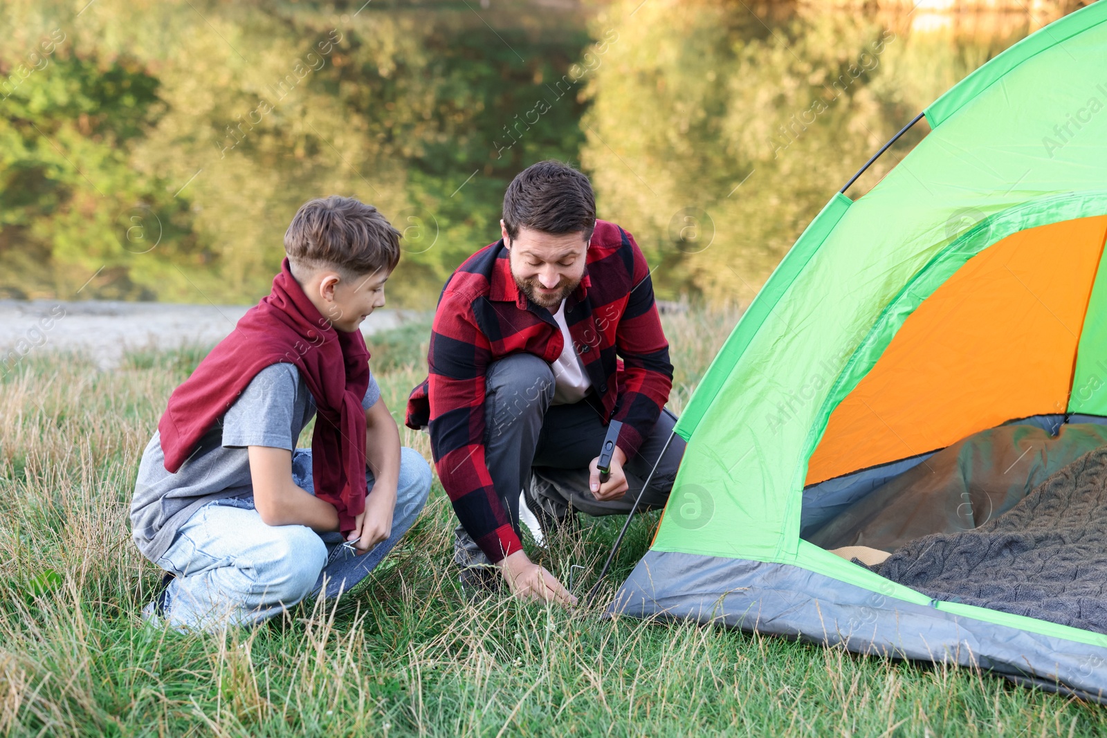 Photo of Father and son setting up camping tent outdoors