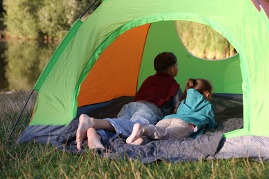 Photo of Brother and sister resting barefoot in camping tent outdoors