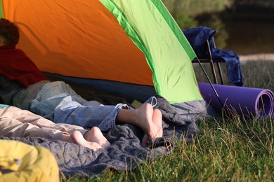 Photo of Brother and sister resting barefoot in camping tent outdoors, closeup