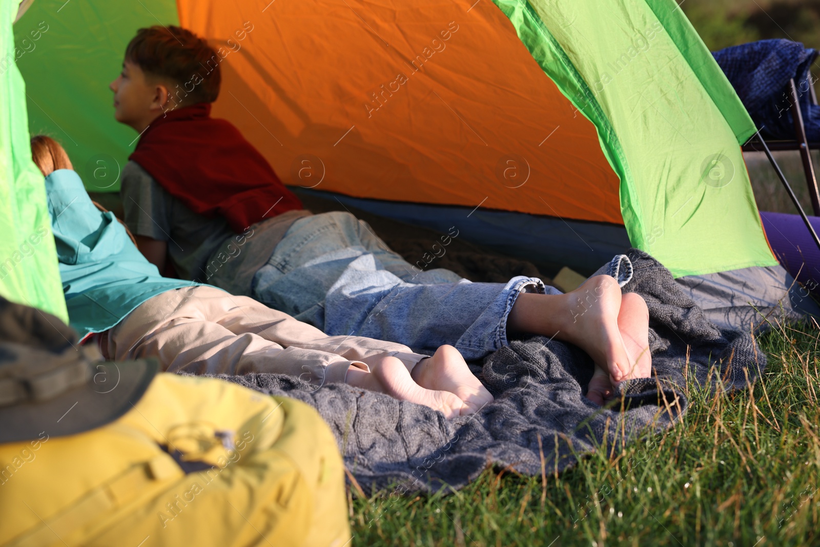 Brother and sister resting barefoot in camping tent outdoors, closeup Photo of Brother and sister resting barefoot in camping tent outdoors, closeup