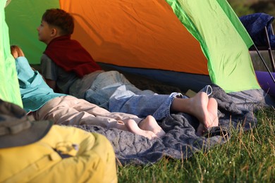 Photo of Brother and sister resting barefoot in camping tent outdoors, closeup