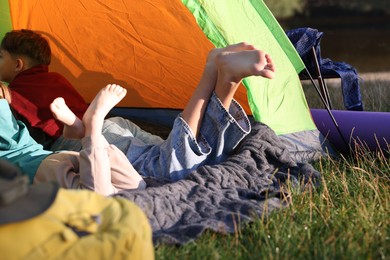 Photo of Brother and sister resting barefoot in camping tent outdoors, closeup