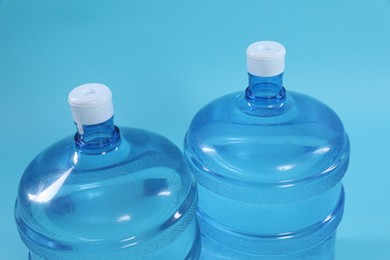 Photo of Cooler bottles with water on light blue background, closeup