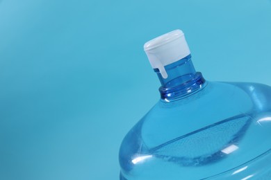 Photo of Cooler bottle with water on light blue background, closeup. Space for text