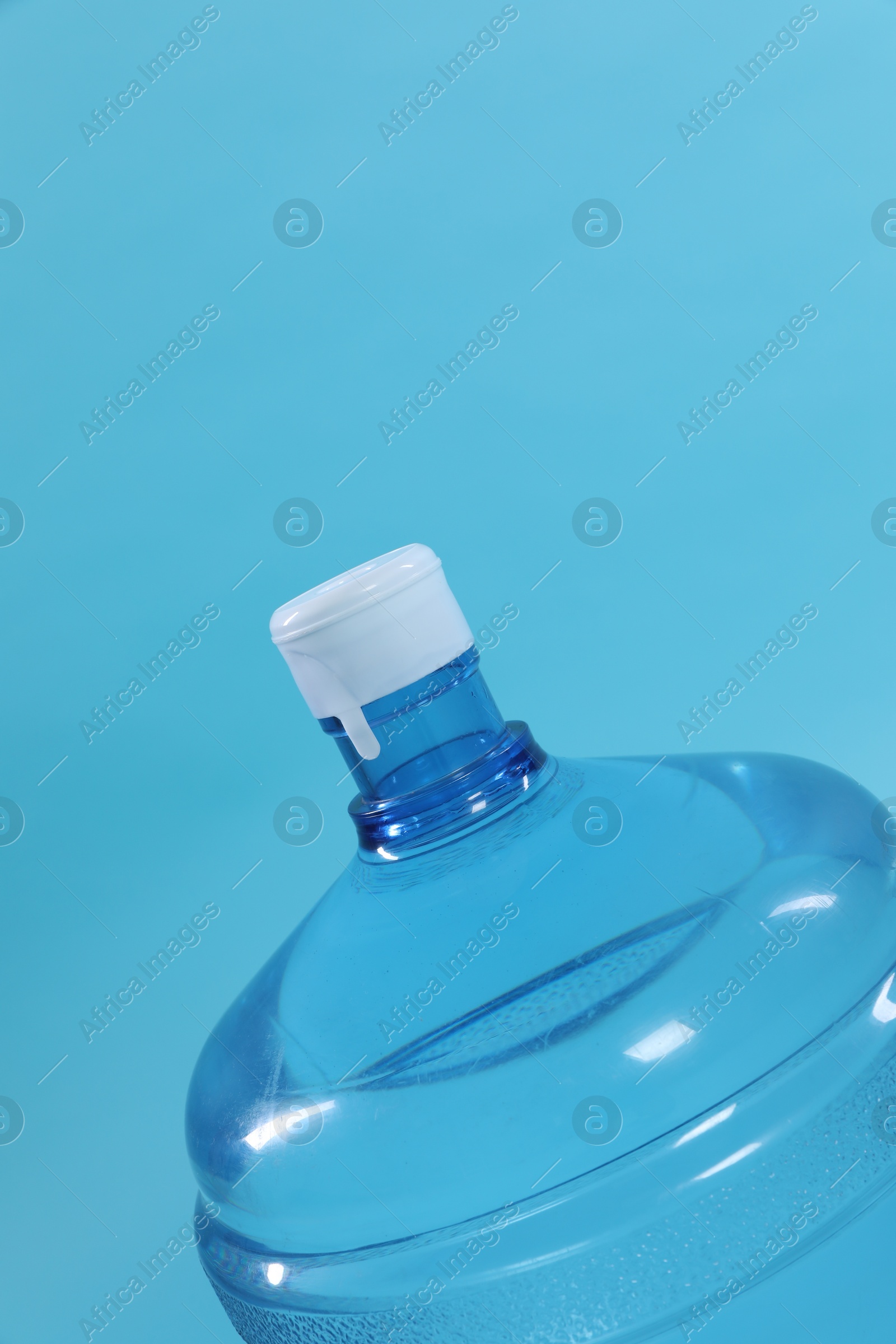 Photo of Cooler bottle with water on light blue background, closeup. Space for text