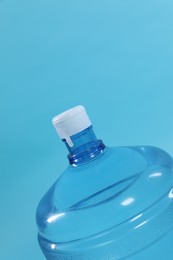 Photo of Cooler bottle with water on light blue background, closeup. Space for text