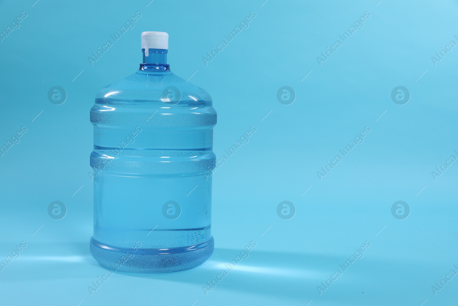 Photo of Cooler bottle with water on light blue background. Space for text