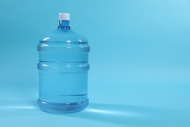 Photo of Cooler bottle with water on light blue background. Space for text
