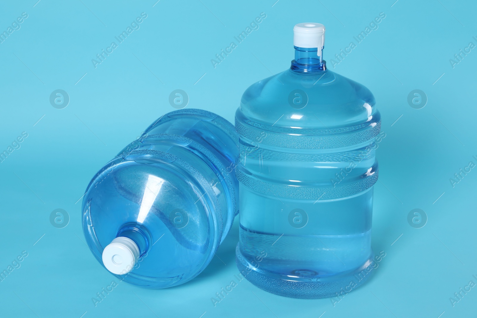 Photo of Cooler bottles with water on light blue background, closeup