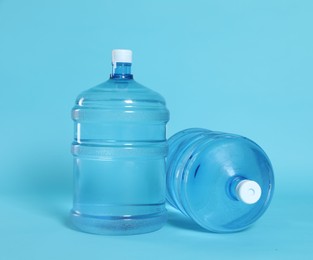 Photo of Cooler bottles with water on light blue background