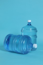 Photo of Cooler bottles with water on light blue background