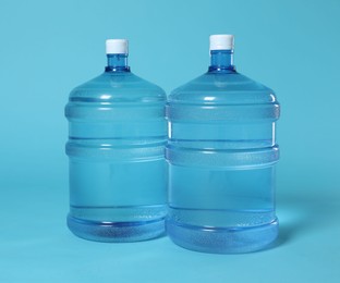 Photo of Cooler bottles with water on light blue background