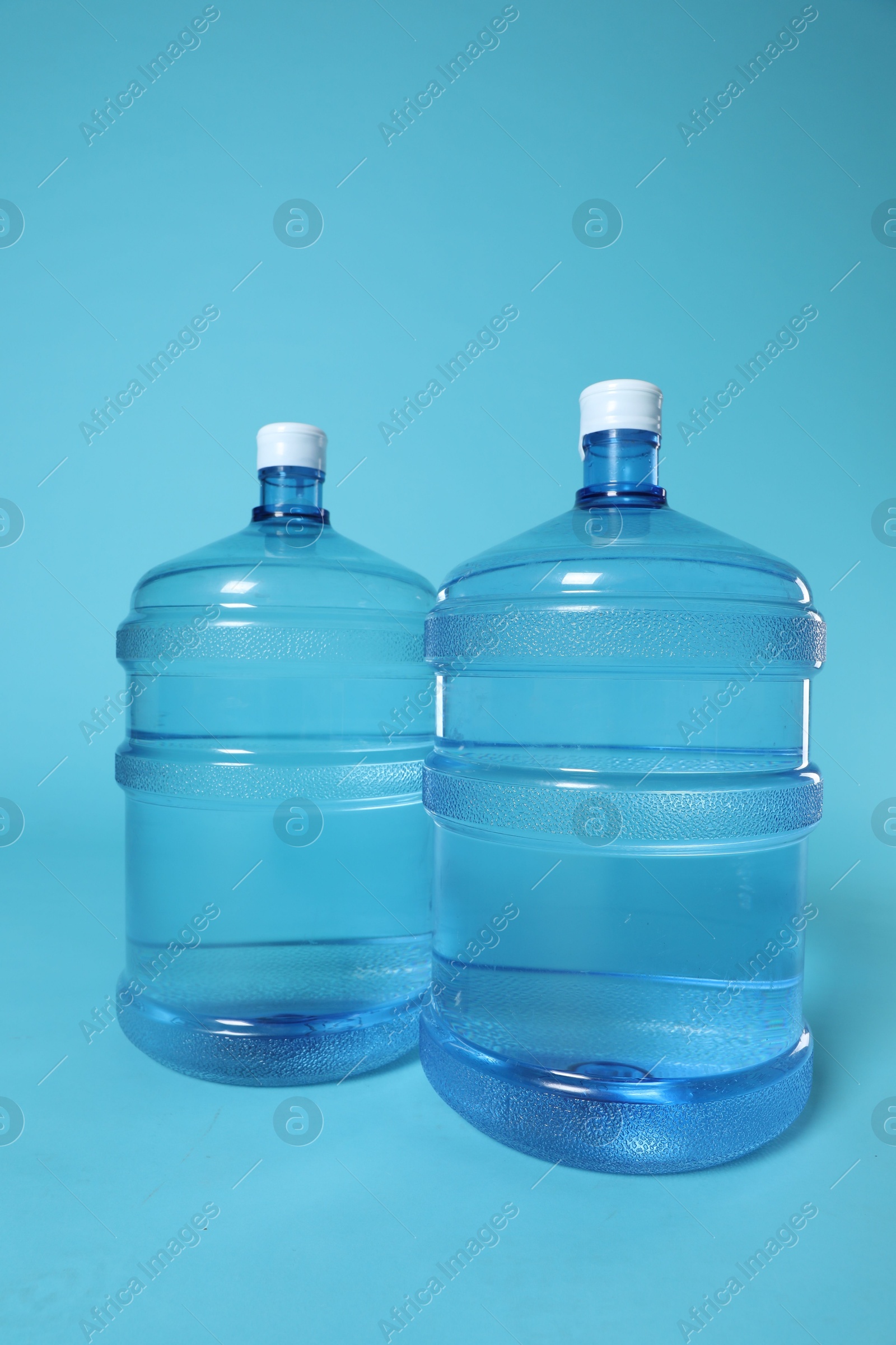 Photo of Cooler bottles with water on light blue background
