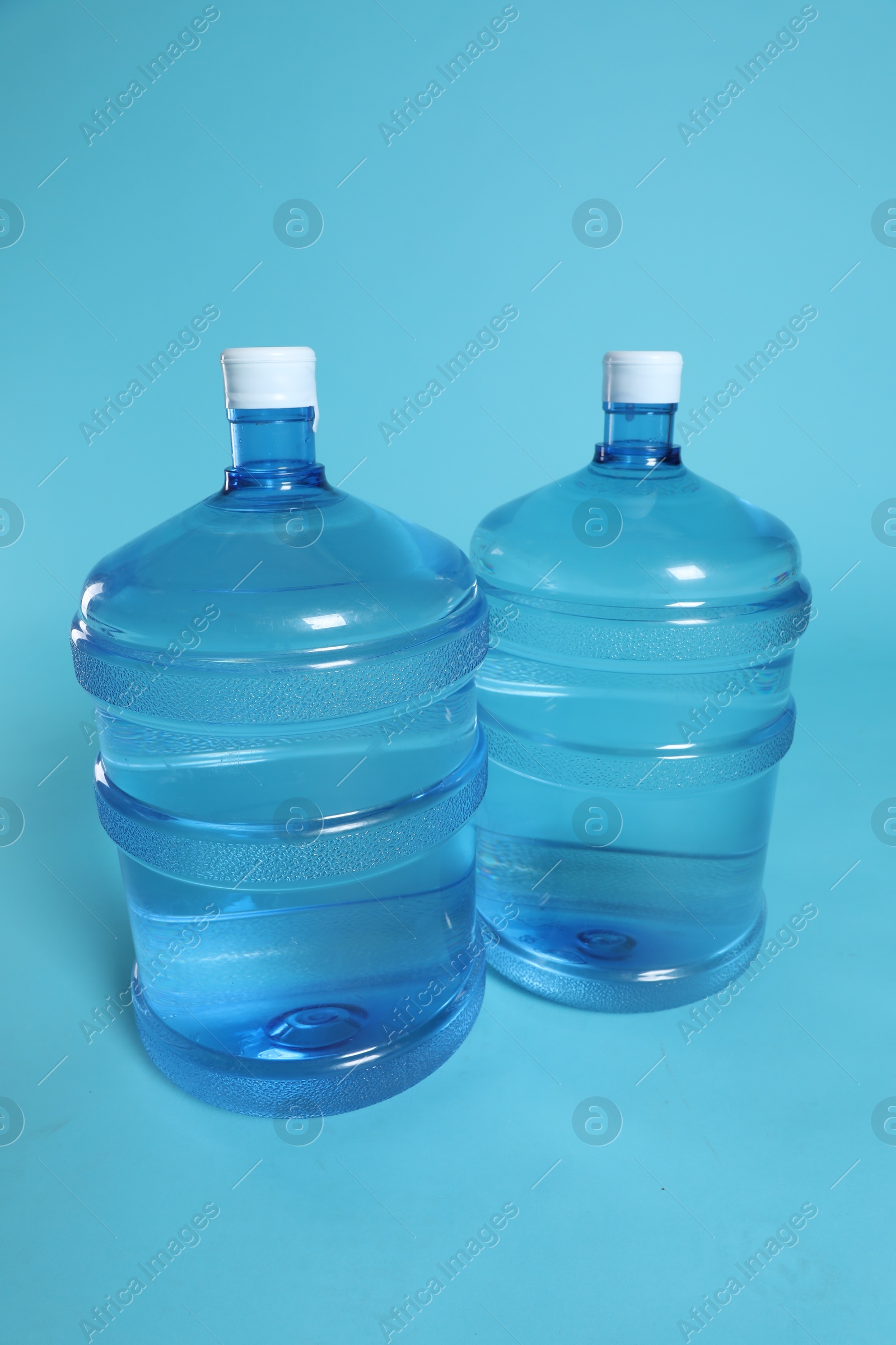 Photo of Cooler bottles with water on light blue background