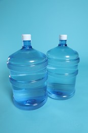 Photo of Cooler bottles with water on light blue background