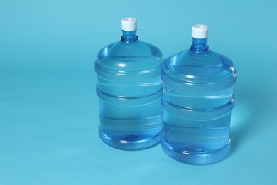 Photo of Cooler bottles with water on light blue background. Space for text