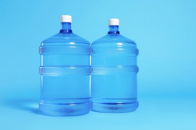 Photo of Cooler bottles with water on light blue background