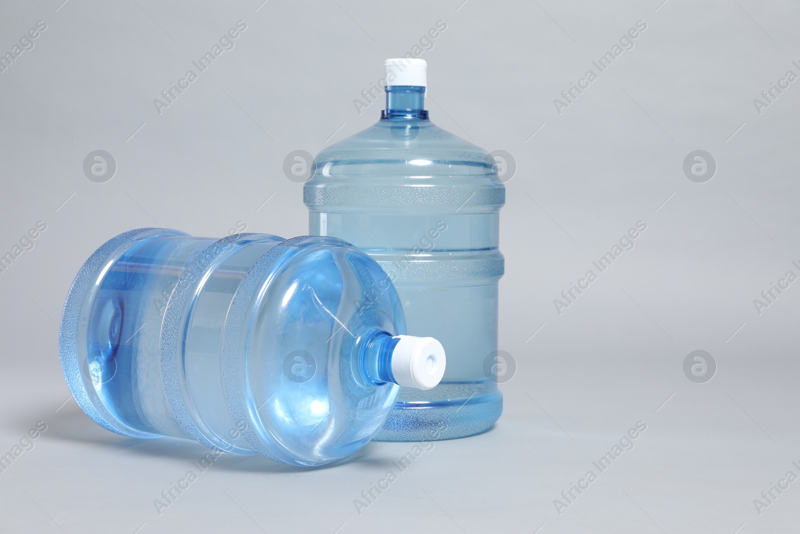 Photo of Cooler bottles with water on light grey background, closeup. Space for text