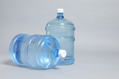 Photo of Cooler bottles with water on light grey background, closeup. Space for text