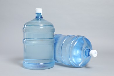 Photo of Cooler bottles with water on light grey background, closeup