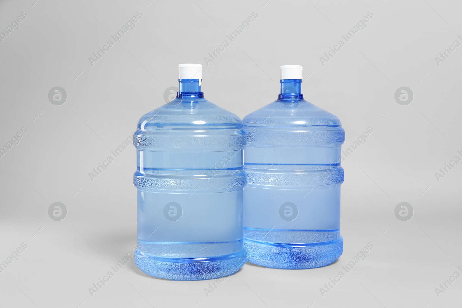 Photo of Cooler bottles with water on light grey background
